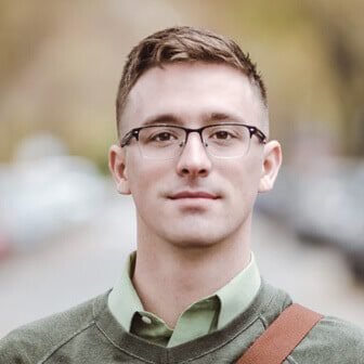 Client testimonial photo of a man wearing glasses and a green sweater